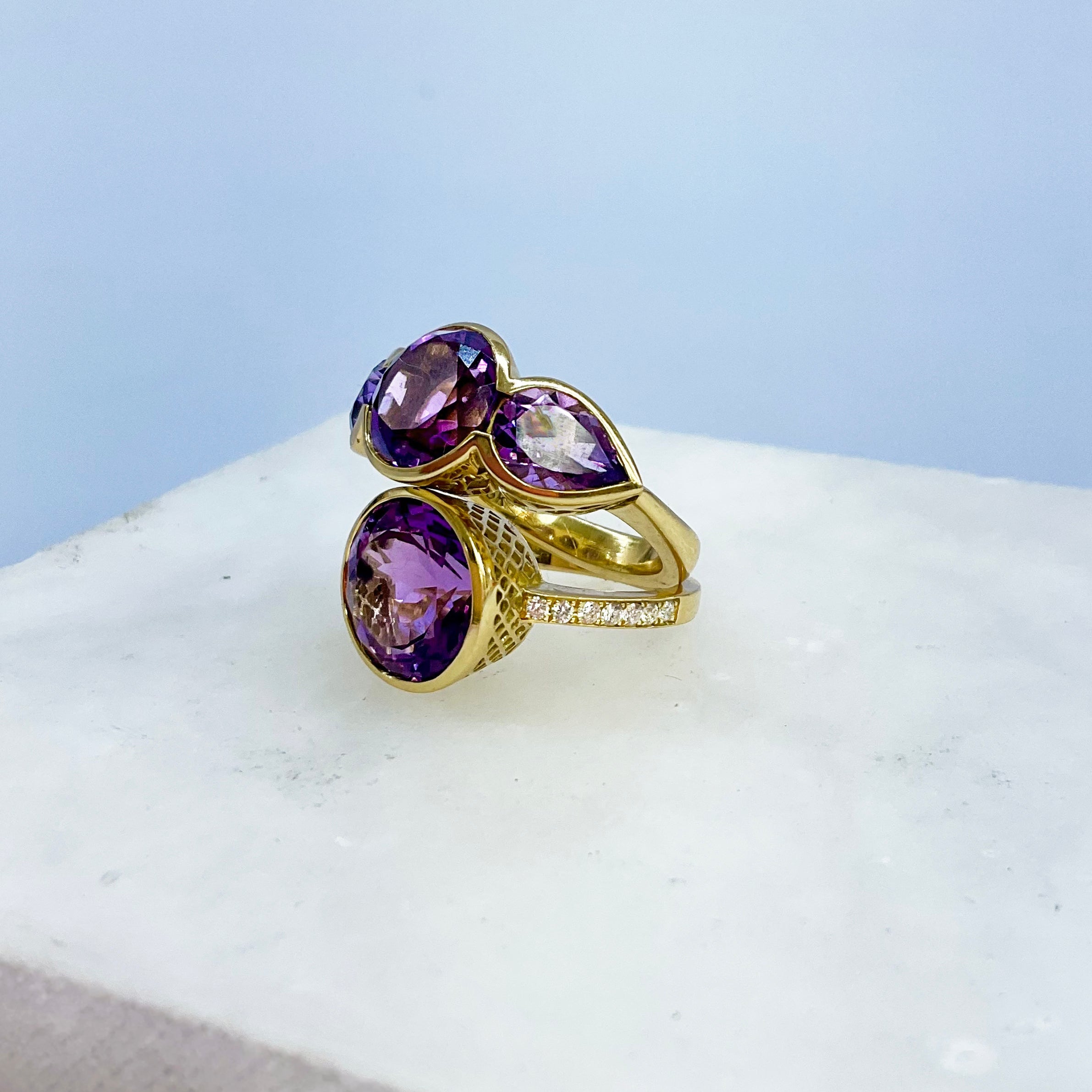 Gold rings with purple anethyst gemstones on a white surface
