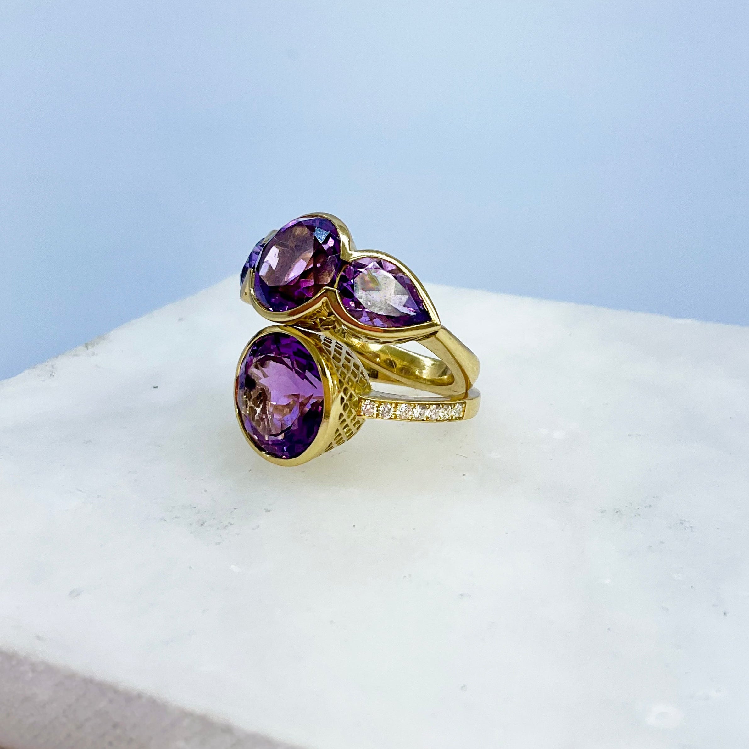 Gold rings with purple amethyst gemstones on a white surface
