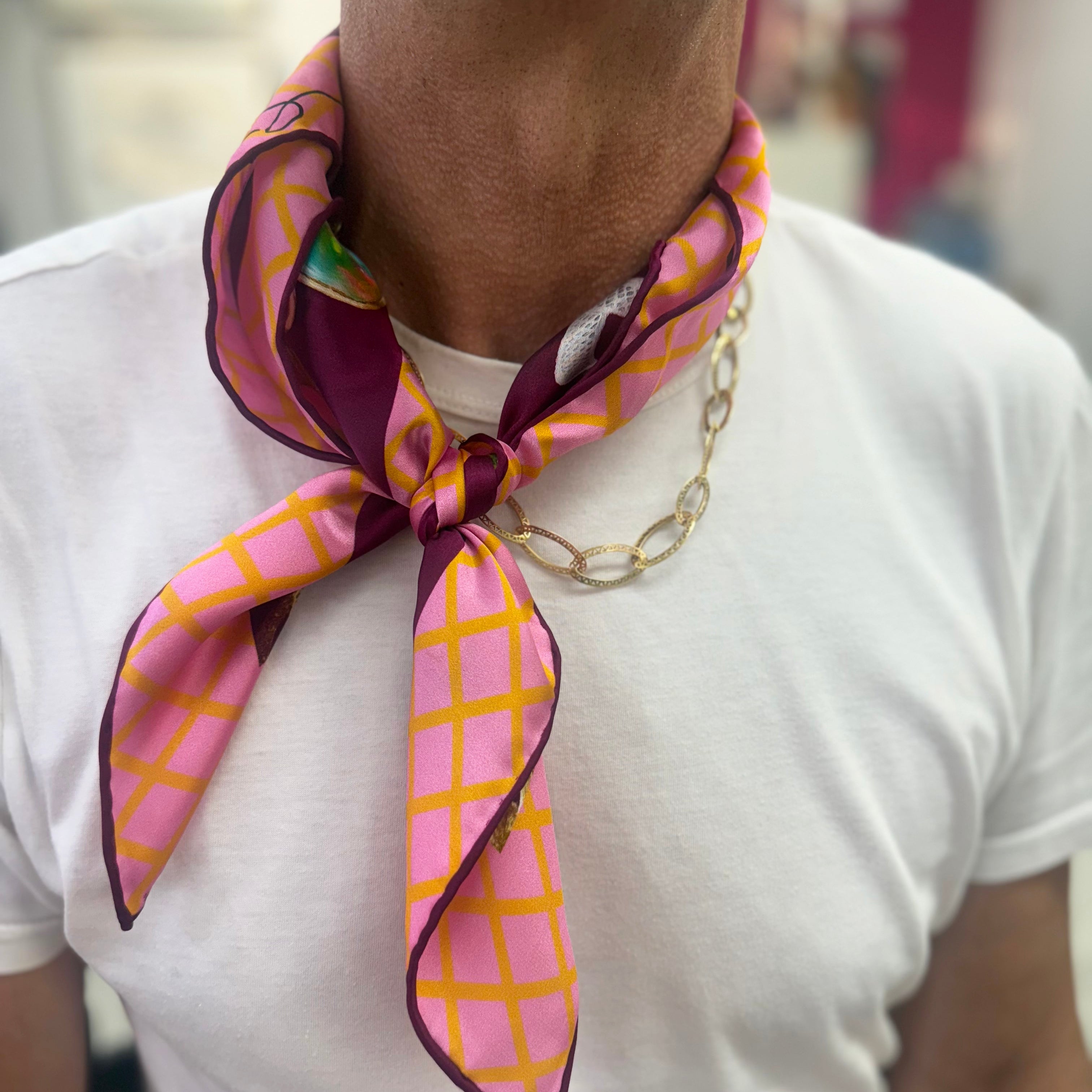 Person wearing a colorful patterned scarf around their neck with a blurred background