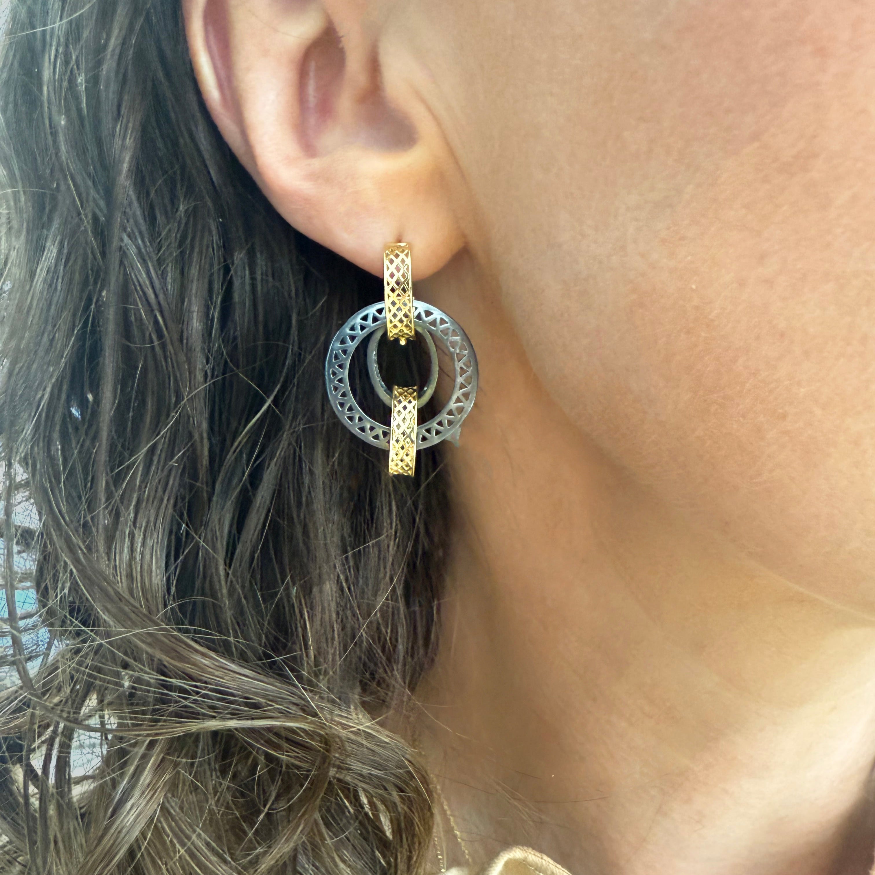 Close-up of an ear wearing a gold and silver hoop earring.