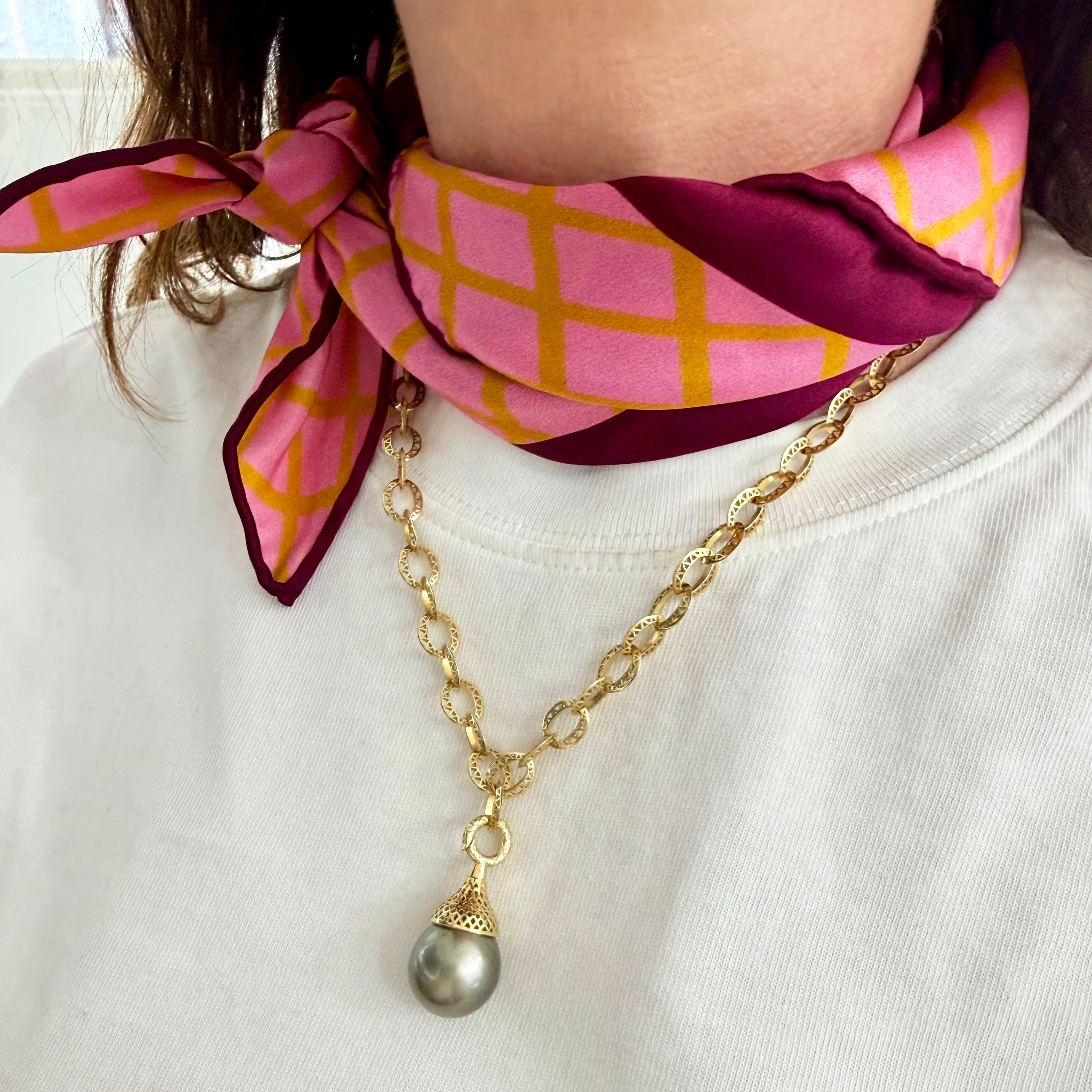 Gold Crownwork link Necklace with a Tahitian pendant and a pink and gold patterned scarf on a white background