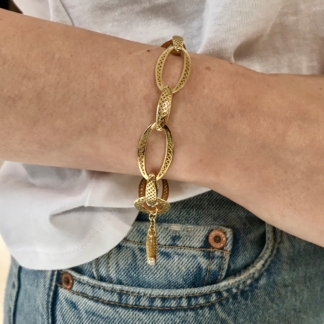 This is an image of a gold link bracelet, perfect for everyday wear, being worn with a white shirt and blue jeans