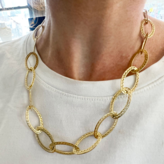 This is a photo of an oval crownwork link cable chain necklace worn with a white T-shirt
