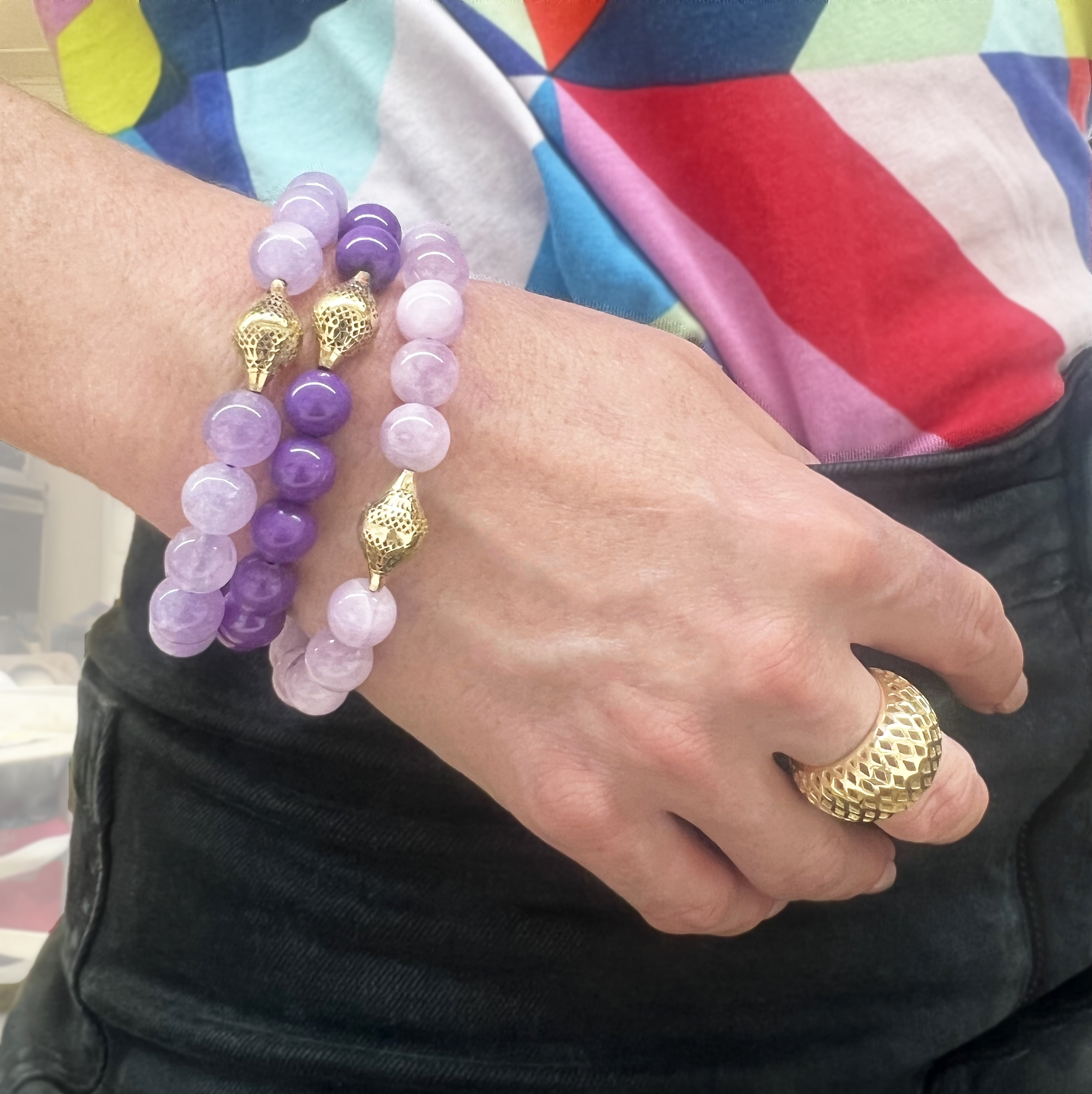 This is a photo of a grouping of purple beaded stretch bracelets and gold crownwork ring