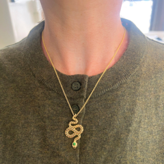 This is an image of an 18k Yellow Gold snake pendant with tsavorite eye and head being worn on an 18" chain