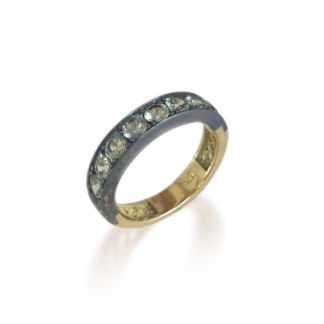 This is a product photo of our green sapphire stacker band - with green sapphires set in oxidized silver on a yellow gold band