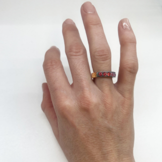 This is an image of a red sapphire stacking band being worn on a ring finger