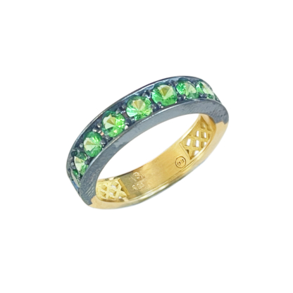 This is a product image of a stacking band with bright green tsavorites set in oxidized silver with a yellow gold band