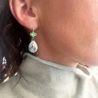 This is an image of a model wearing a pair of Aquaprase™ drop earrings with 4 emeralds set in a four lead clover on the wire