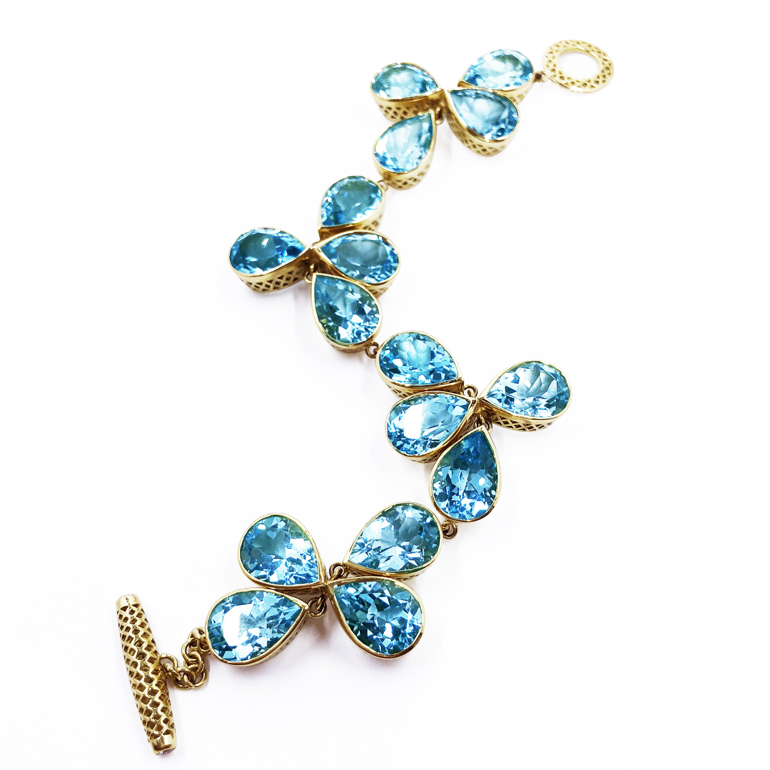 This is a photo of a gold crownwork bracelet with pear shaped blue topaz stones