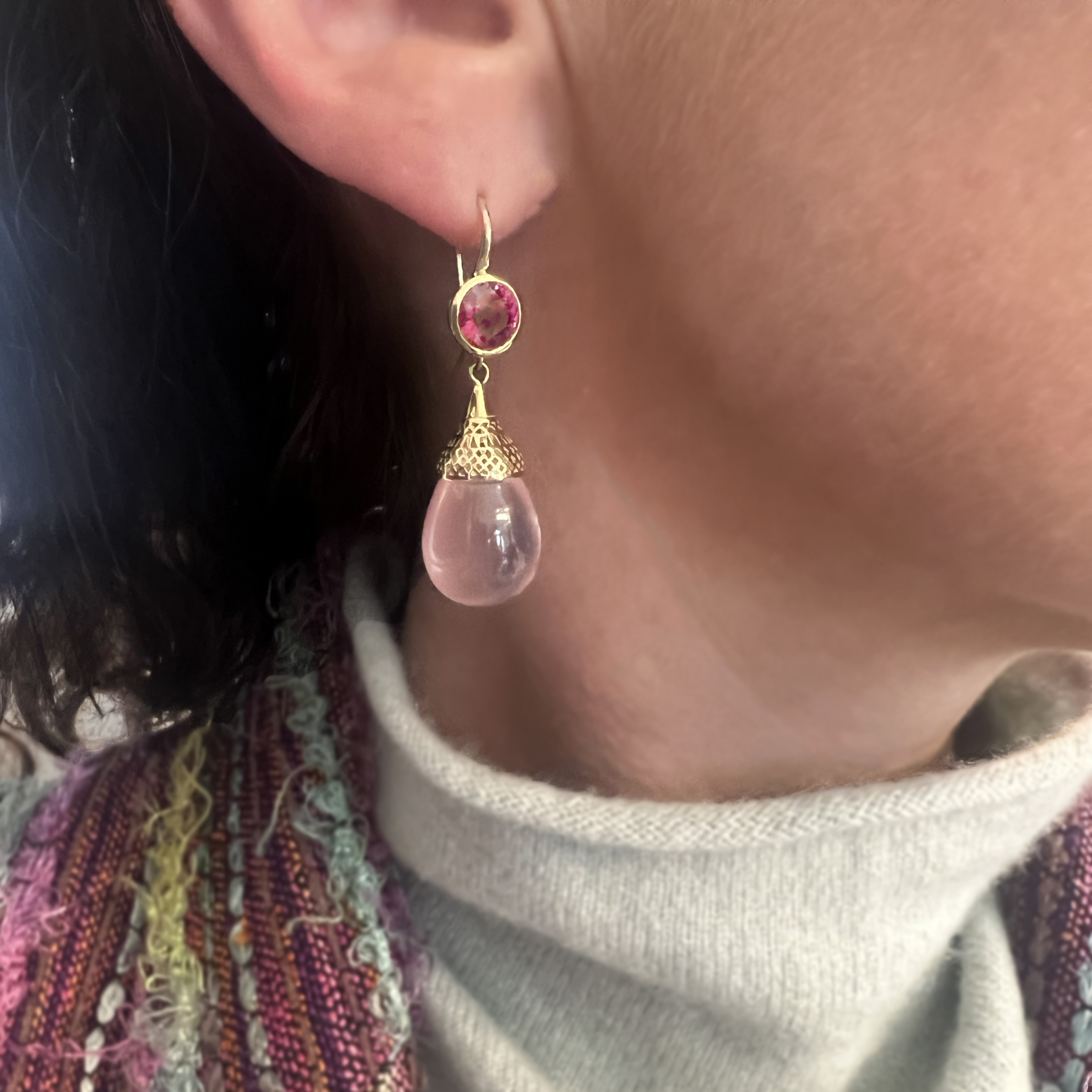 This is an image of bright pink rhodolite garnet earrings on hooks with pale pink rose quartz drops being worn by a model