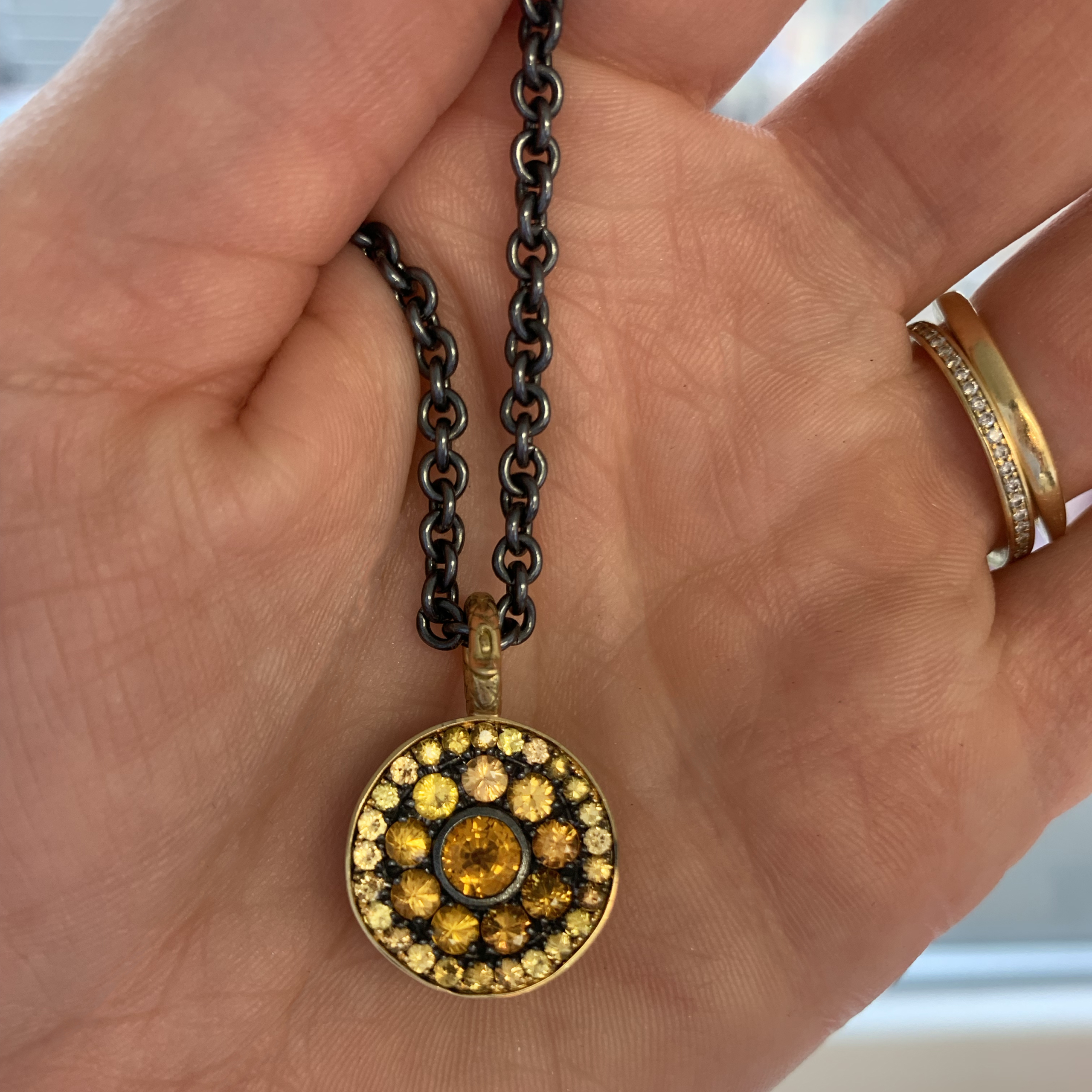 This is a photo of a pave yellow sapphire pendant on an oxidized silver chain