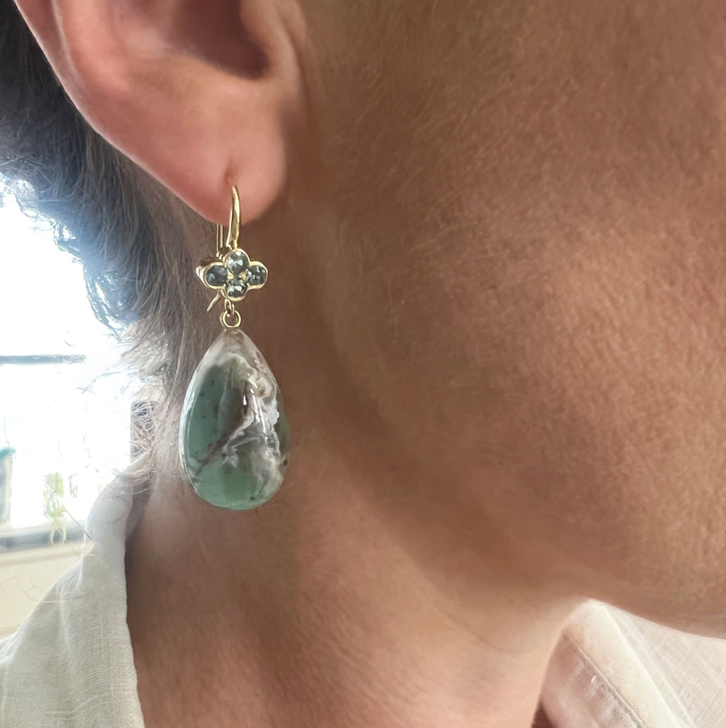 This is a photo of the 18K Yellow Gold clover with bezel set green sapphires and Aquaprase drops worn on the ear