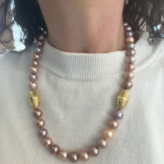 This is an image of multi colored pearl necklace with gold accents being worn with white tee