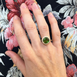 18k yellow gold 10mm Crownwork bezel set Green Tourmaline ring with pave diamond surround being worn on the hand