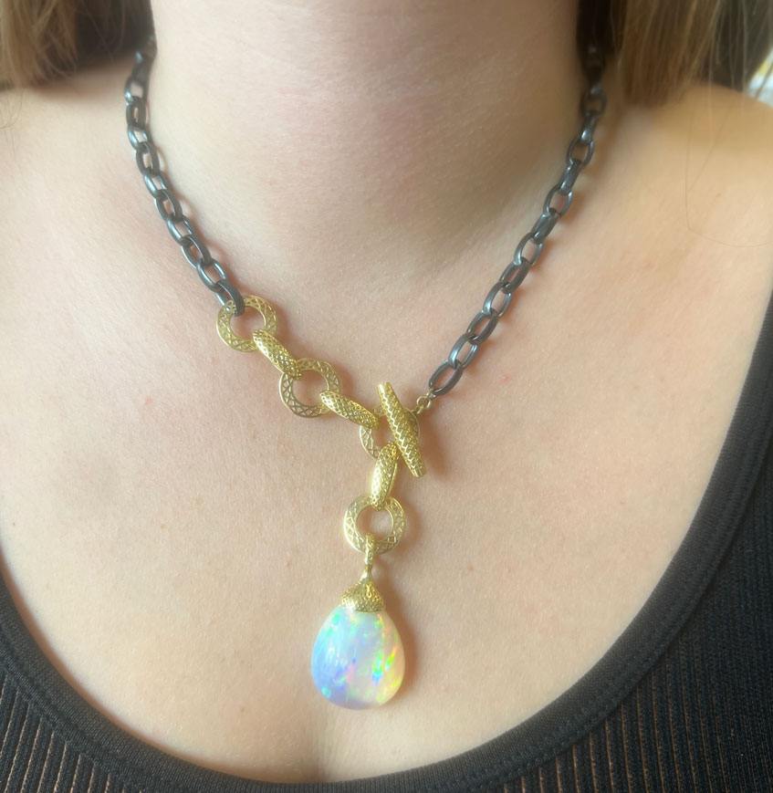 This is a photo of an Ethiopian Opal Pendant on an oxidized silver chain with gold crownwork links