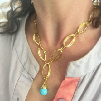 This is an image of a bright blue sonoran turquoise pendant being works on a chunky gold chain