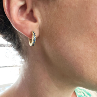This is a photo of an 18k YG huggie earring with pave blue sapphires