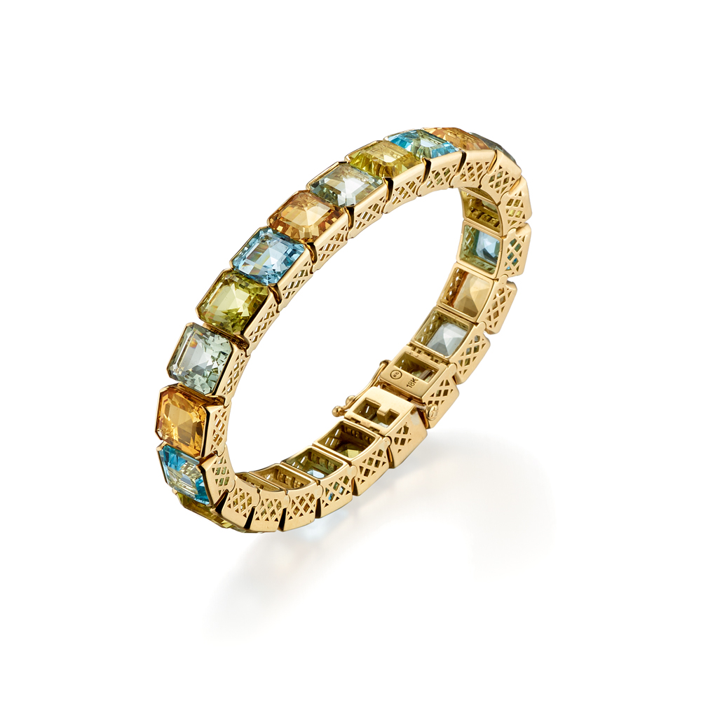 This is a product shot of an 18k yellow gold crownwork channel link bracelet with green citrine, yellow citrine, blue topaz and and green amethyst gemstones