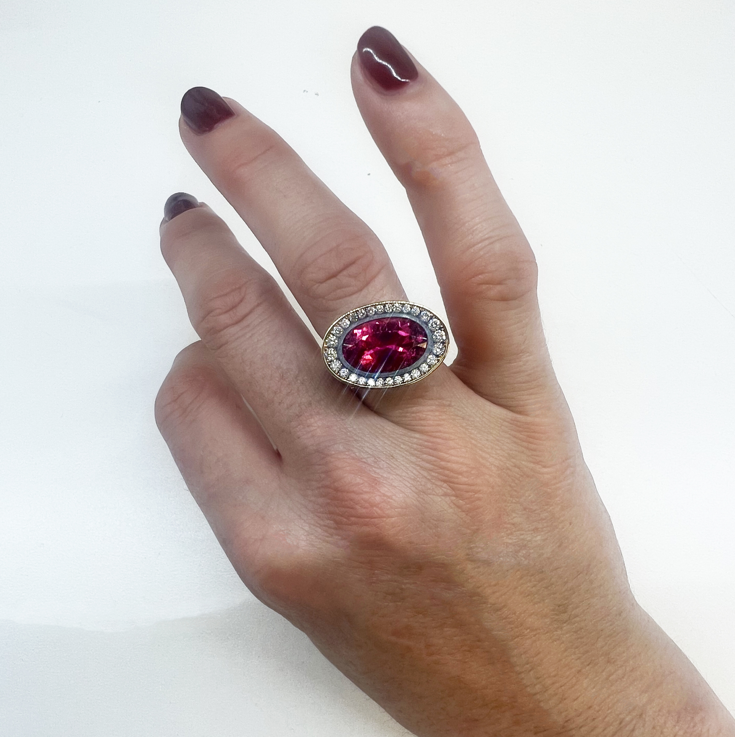 This is a photo of am east / west cocktail ring with oval pink tourmaline and pave diamond surround