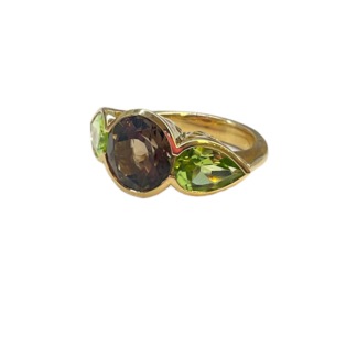 This is a product shot if an 18k Yellow gold Crownwork scallop ring with pear shape green peridot side stones and oval smoky quartz center stone